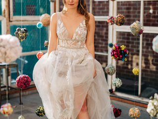 A woman stands in a wedding dress in a room full of colorful pompoms