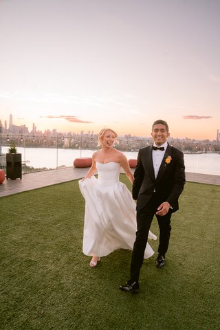 two people holding hands walking with the new york city background behind them