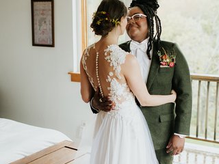 a white person in a wedding dress and a black person in a green suit embrace each other on their wedding day