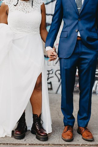 close up of two people's shoes, one person in a suit and the other in a wedding dress wearing doc marten boots