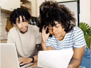 two people look at a laptop with overwhelm and stress on their faces