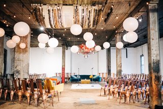 a room set up for a wedding ceremony in the round with lots of chairs, rugs, couches, and disco balls and balloons hanging from the ceiling