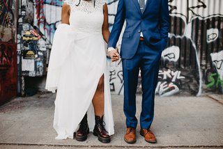 close up of two people's shoes, one person in a suit and the other in a wedding dress wearing doc marten boots