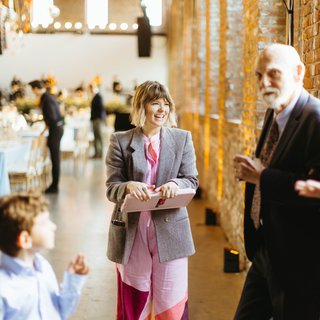 A white woman in a colorful jumpsuit holding a clipboard