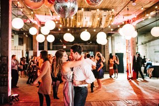 Two people dance underneath balloons and disco balls