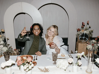 Two marriers raise a glass at their table decked out with disco balls