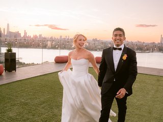 two people holding hands walking with the new york city background behind them