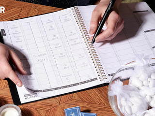 Close up image of someone's hands as they hold a pen and a wedding planning guidebook