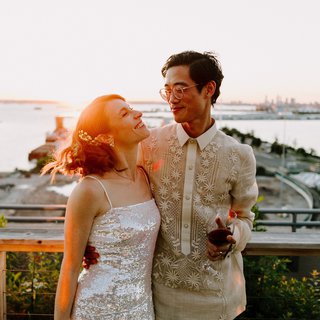 two people smiling at each other on a deck with flowers behind them