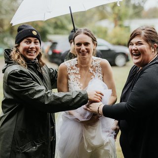 two people holding an ubmrella over a person in a wedding dress