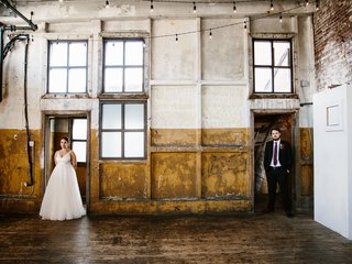 Two people stand in wedding attire in separate doorways in a large room