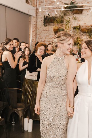 two white women holding hands as they recess down the altar after their wedding ceremony