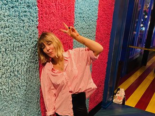 amy leans against a colorful wall, smiling at the camera